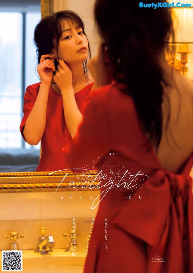 A woman in a red dress looking at herself in the mirror.
