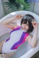 A woman in a bathing suit and goggles sitting in a bathtub.