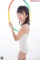 A woman in a white bodysuit holding a hula hoop.