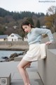 A woman leaning against a wall with her legs crossed.