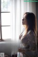 A woman standing in front of a window in a room.