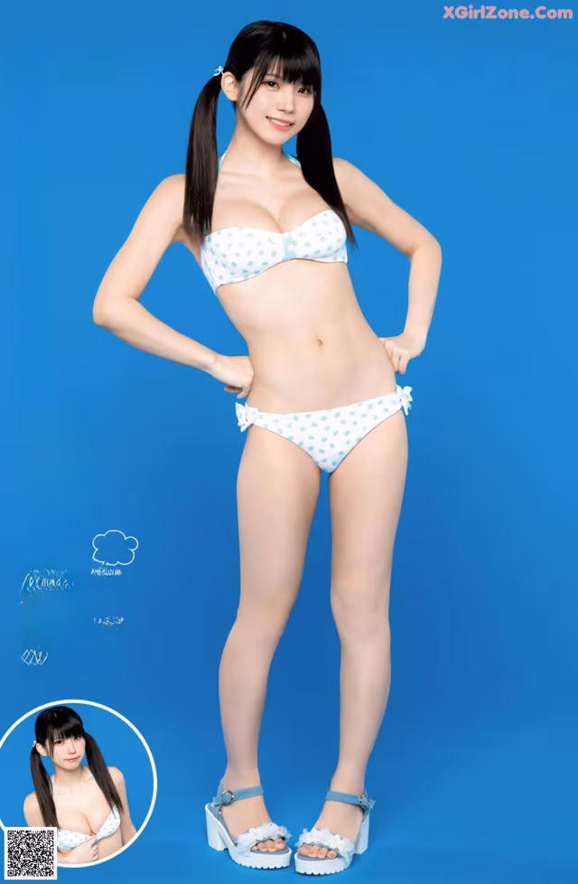 A woman in a blue and white polka dot bikini posing for a picture.