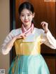 A woman in a blue and yellow hanbok is posing for a picture.