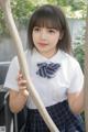 A young woman in a school uniform holding a baseball bat.