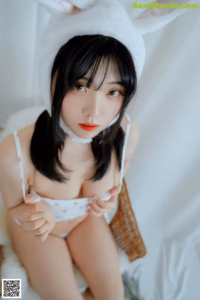 A woman in a bunny costume sitting on a bed.