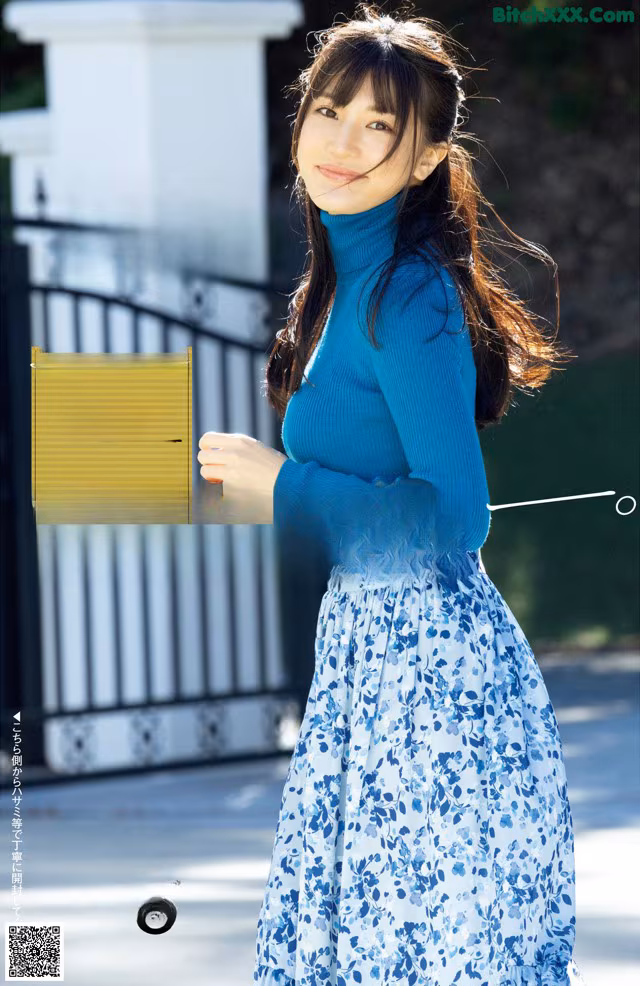 A woman in a blue turtle neck sweater and a blue skirt.