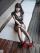 A woman sitting on a white bench wearing black stockings and red shoes.