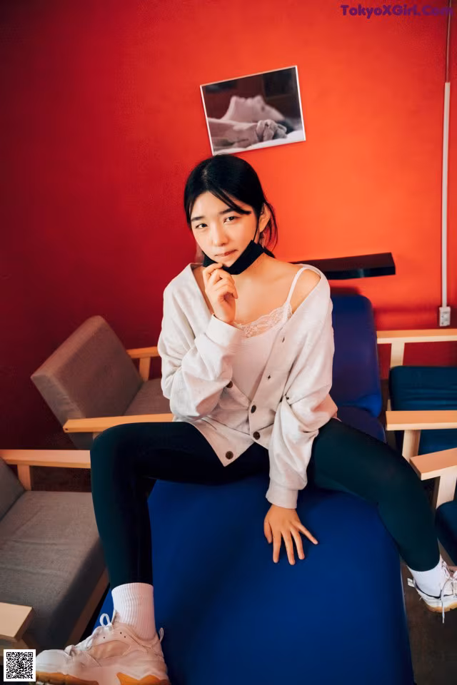 A woman sitting on a blue chair in a room.