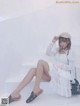 A woman sitting on a white staircase wearing a white dress and a hat.