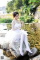 A woman sitting on a rock holding a bouquet of flowers.