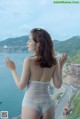 A woman in a white lingerie standing on a balcony overlooking the ocean.