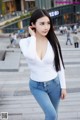 A woman in a white top and blue jeans posing for a picture.