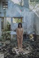 A naked woman standing in an abandoned building.