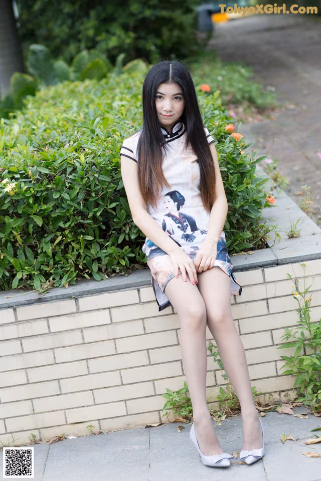 A woman sitting on a brick wall with her legs crossed.