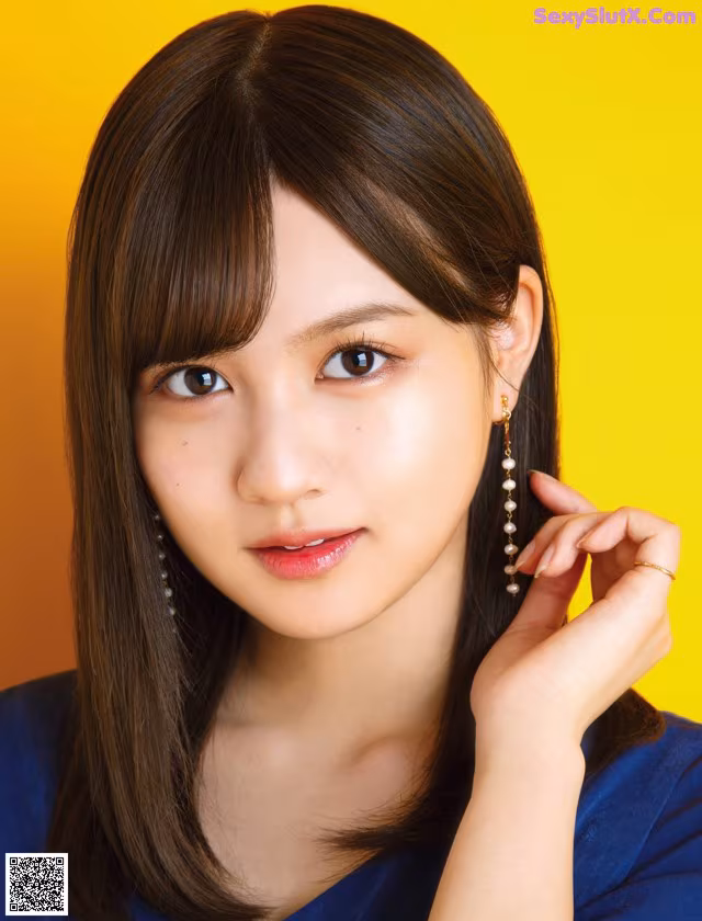 A woman with long brown hair wearing a blue shirt.