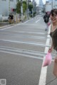 A woman walking down the street holding a pink bag.